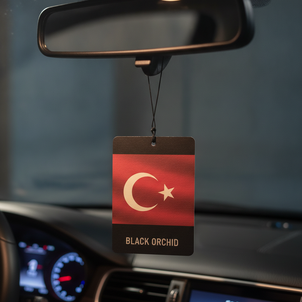 Close-up of a premium car air freshener with a Turkish flag design, hanging in a luxurious car interior under soft lighting.